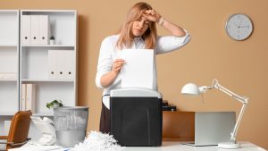 office worker using a office shredding thinking about if a professional shredding service is a better option
